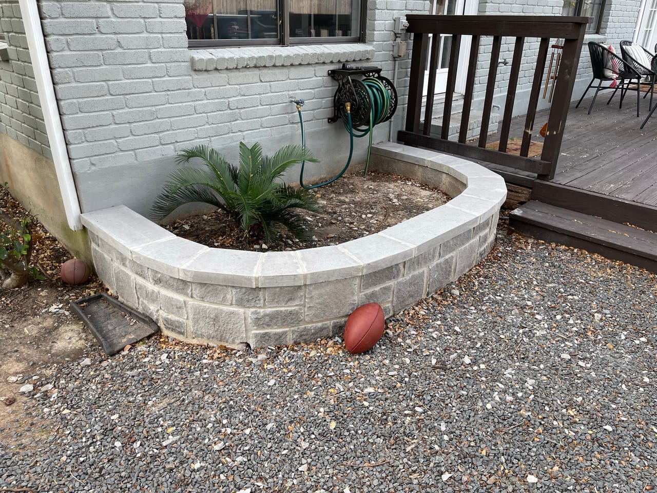Curved stone seat wall with gravel bed beside a house deck in Pflugerville, TX
