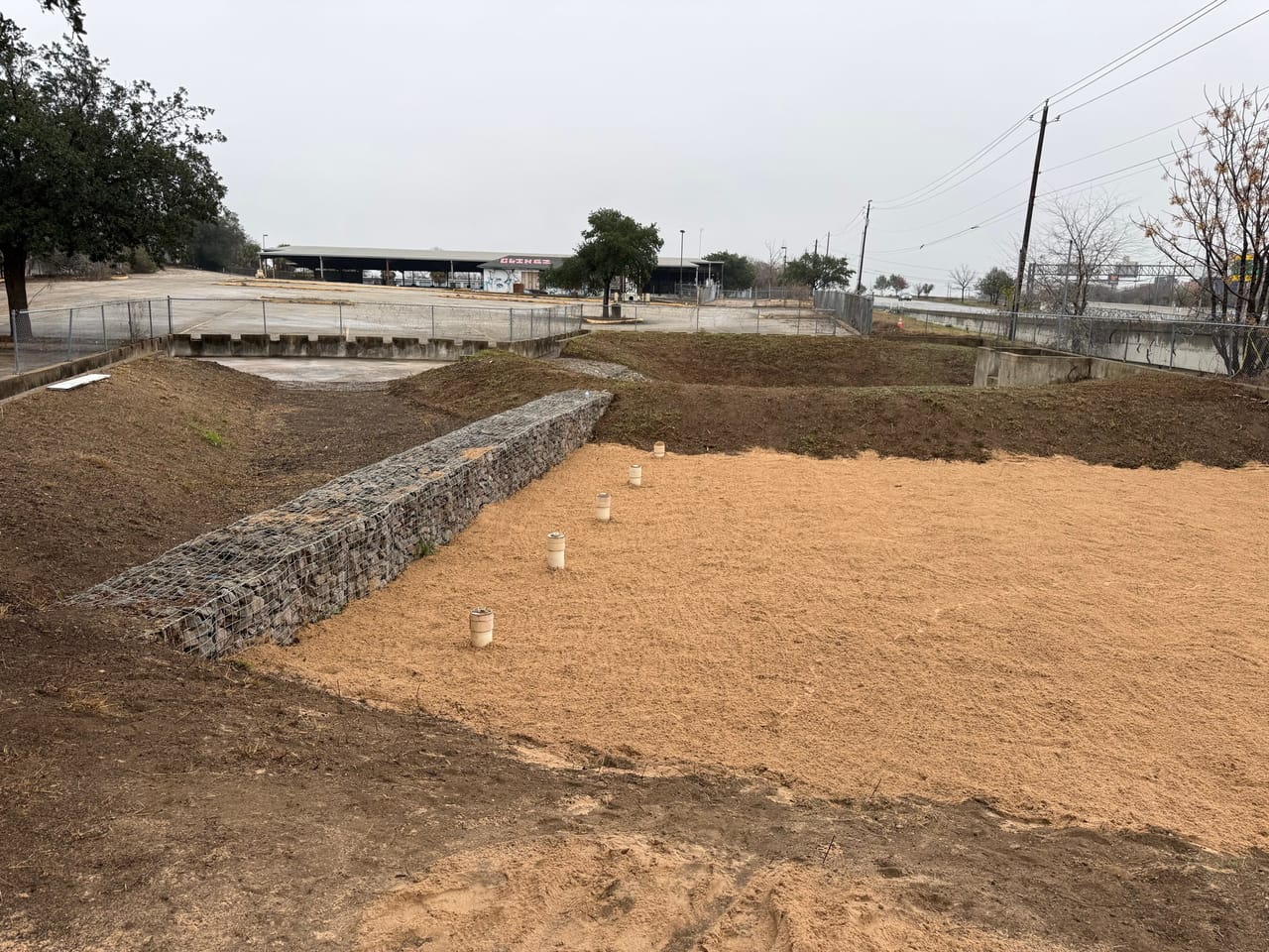 Gabion rock basket wall holding a freshly graded hydromulched detention basin in Maxwell, TX
