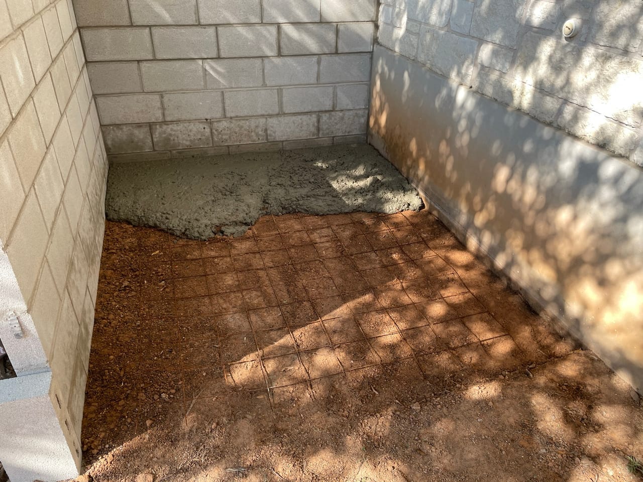 Inside a stone walled courtyard with bare dirt base and dappled shade by Corral Bros in Central Texas