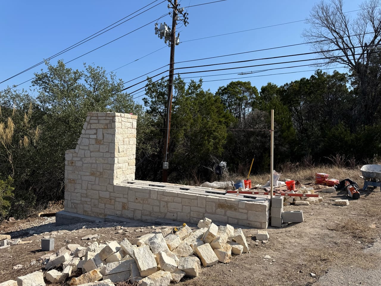 Limestone entrance wall and column built out along a lot by Corral Bros in Central Texas