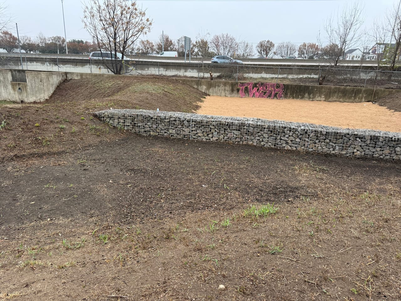 Long gabion rock wall running along the graded detention basin edge in Kyle, TX