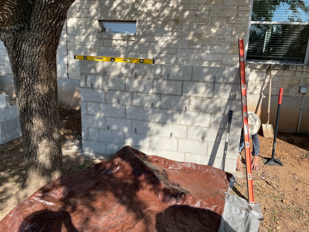 Stone block wall going up with a level set on top course in Liberty Hill, TX