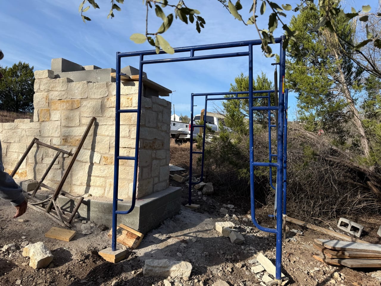 Stone column and wall with blue steel frame staged nearby by Corral Bros in Central Texas