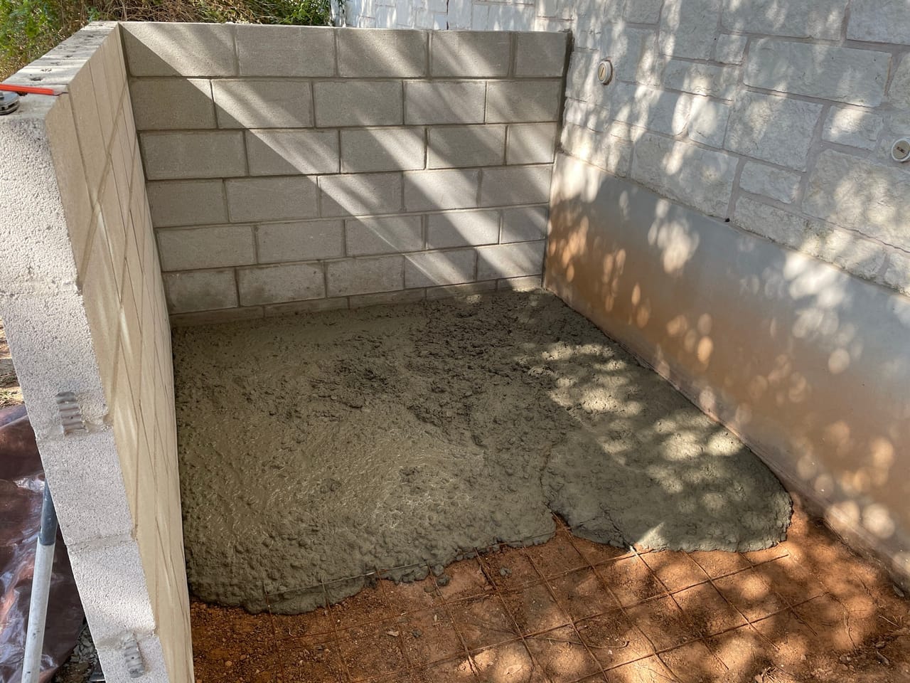 Stone wall corner with gravel base being spread across the floor by Corral Bros in Central Texas
