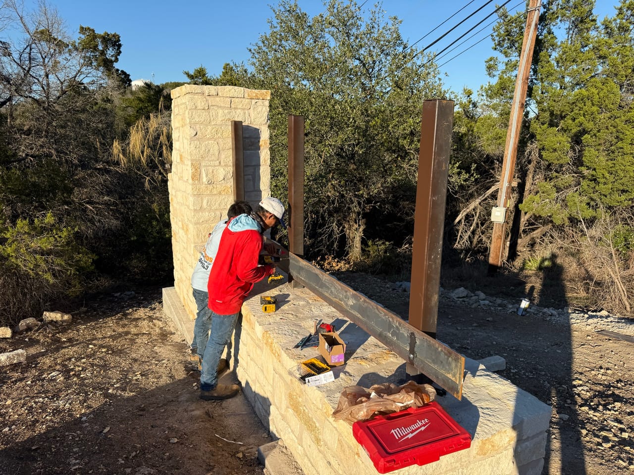 Worker fitting steel posts to a limestone sign column by Corral Bros in Central Texas