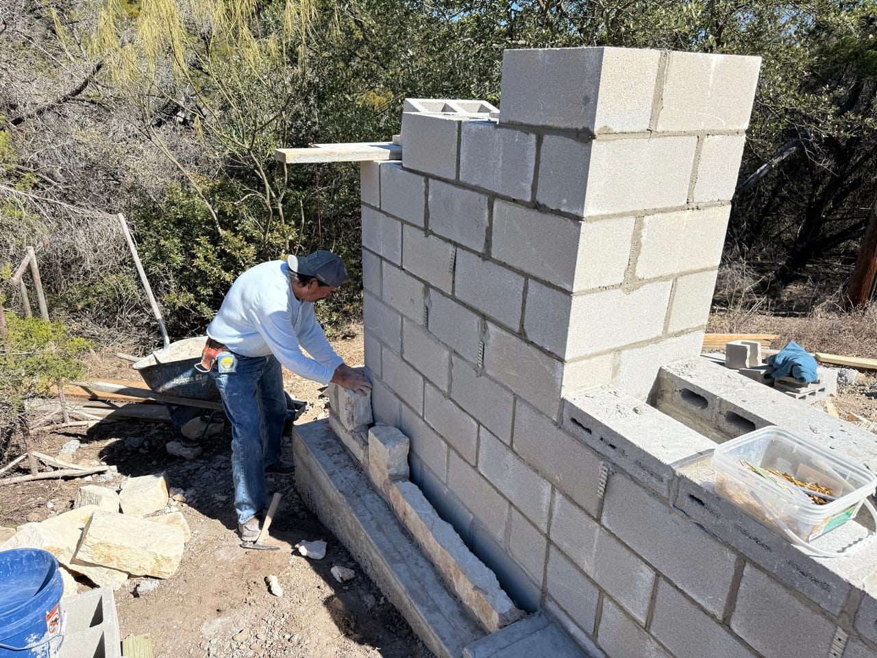 Worker mixing beside a partly built concrete block wall by Corral Bros in Central Texas