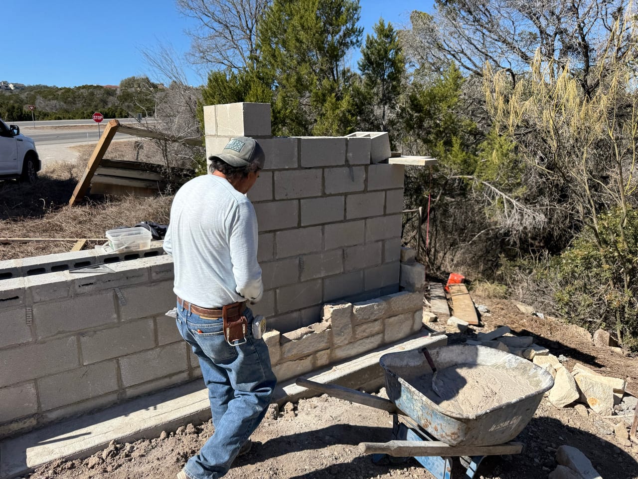Worker in white shirt standing at concrete block wall corner by Corral Bros in Central Texas