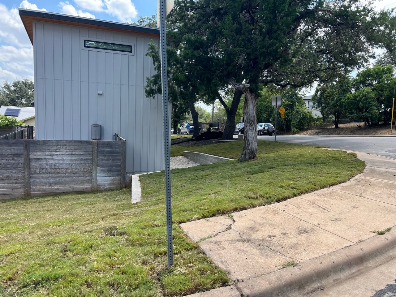 Corner lot with new sod along a curving sidewalk and building by Corral Bros in Central Texas