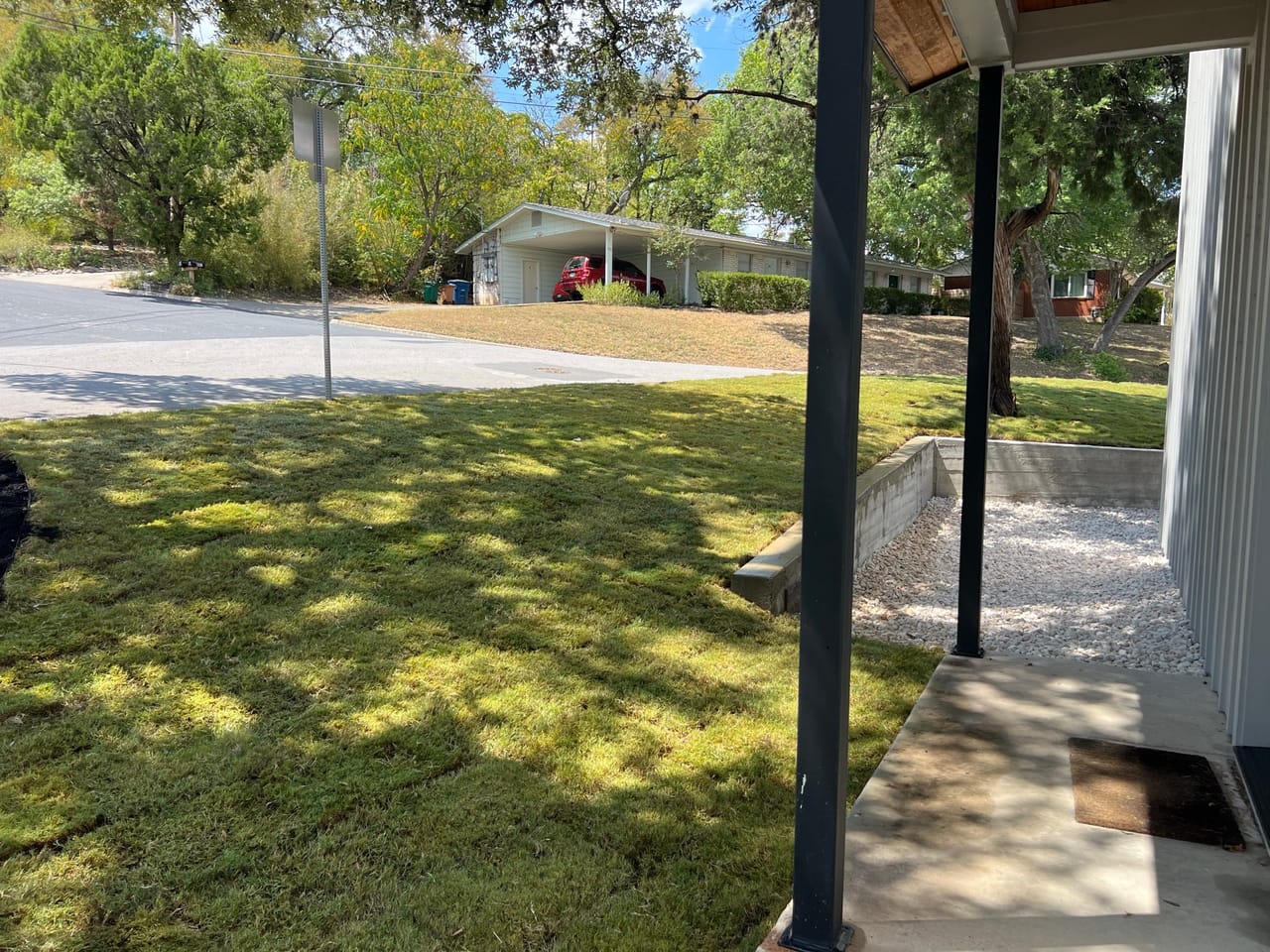 Green lawn viewed from under a porch with column blocking view by Corral Bros in Central Texas