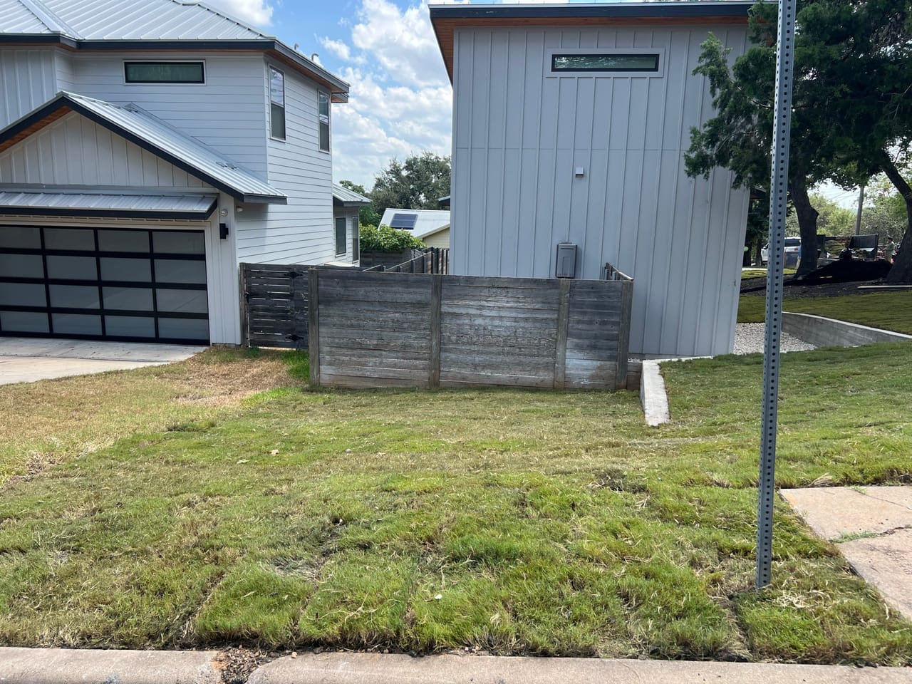 New sod front lawn at a white modern home with black garage in Spicewood, TX