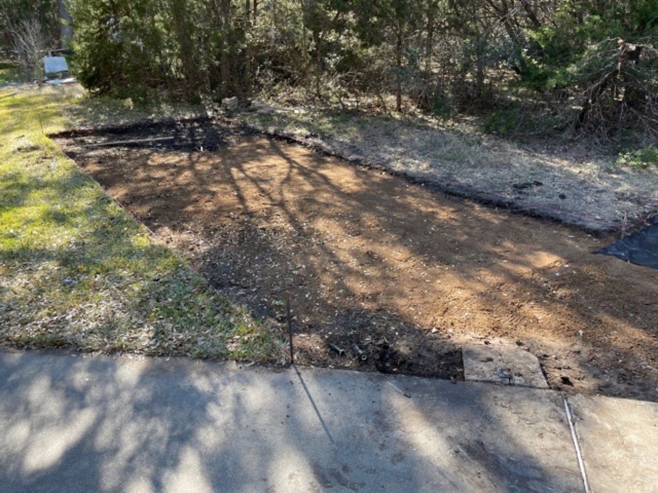 Black pond liner laid on shaded ground near a concrete edge in Austin, TX