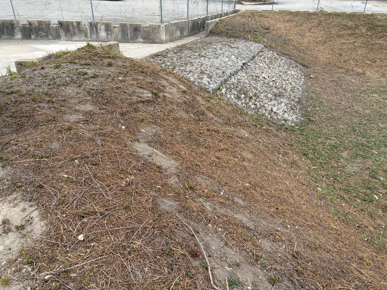 Detention pond slope with a rock lined chute and seeded dirt in Leander, TX