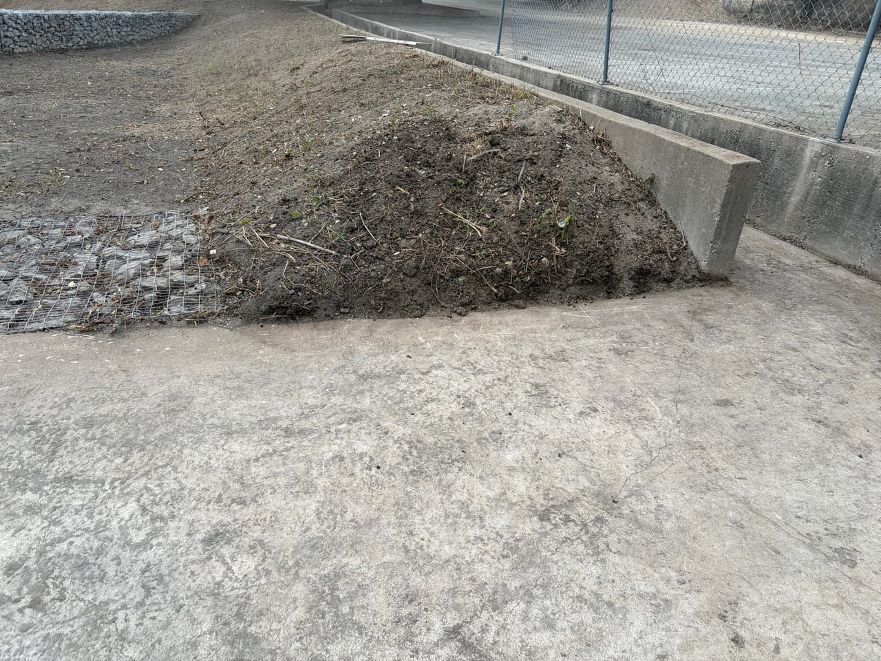 Fresh soil berm on a concrete channel bank with gravel bottom by Corral Bros in Central Texas
