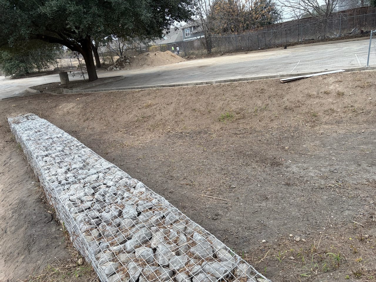 Neat gabion rock chute running down into a concrete drainage channel in Leander, TX
