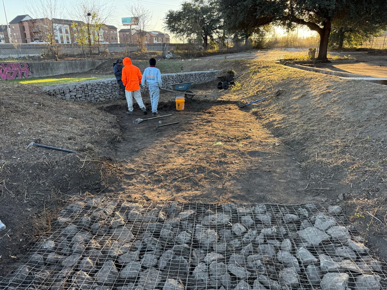 Two workers on a slope above a rock filled gabion channel bottom in Austin, TX