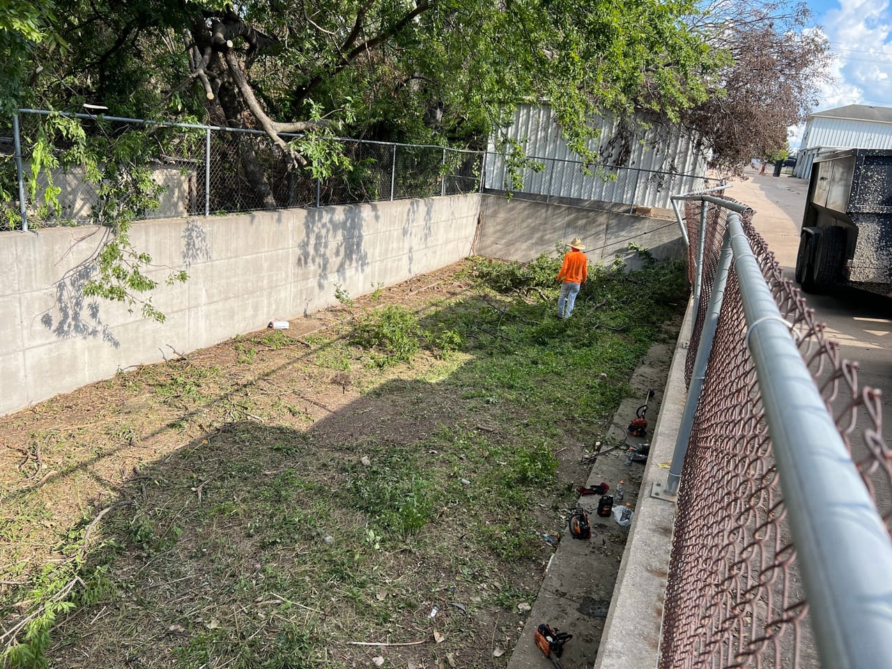Worker in a concrete drainage channel with chain link fence in Georgetown, TX