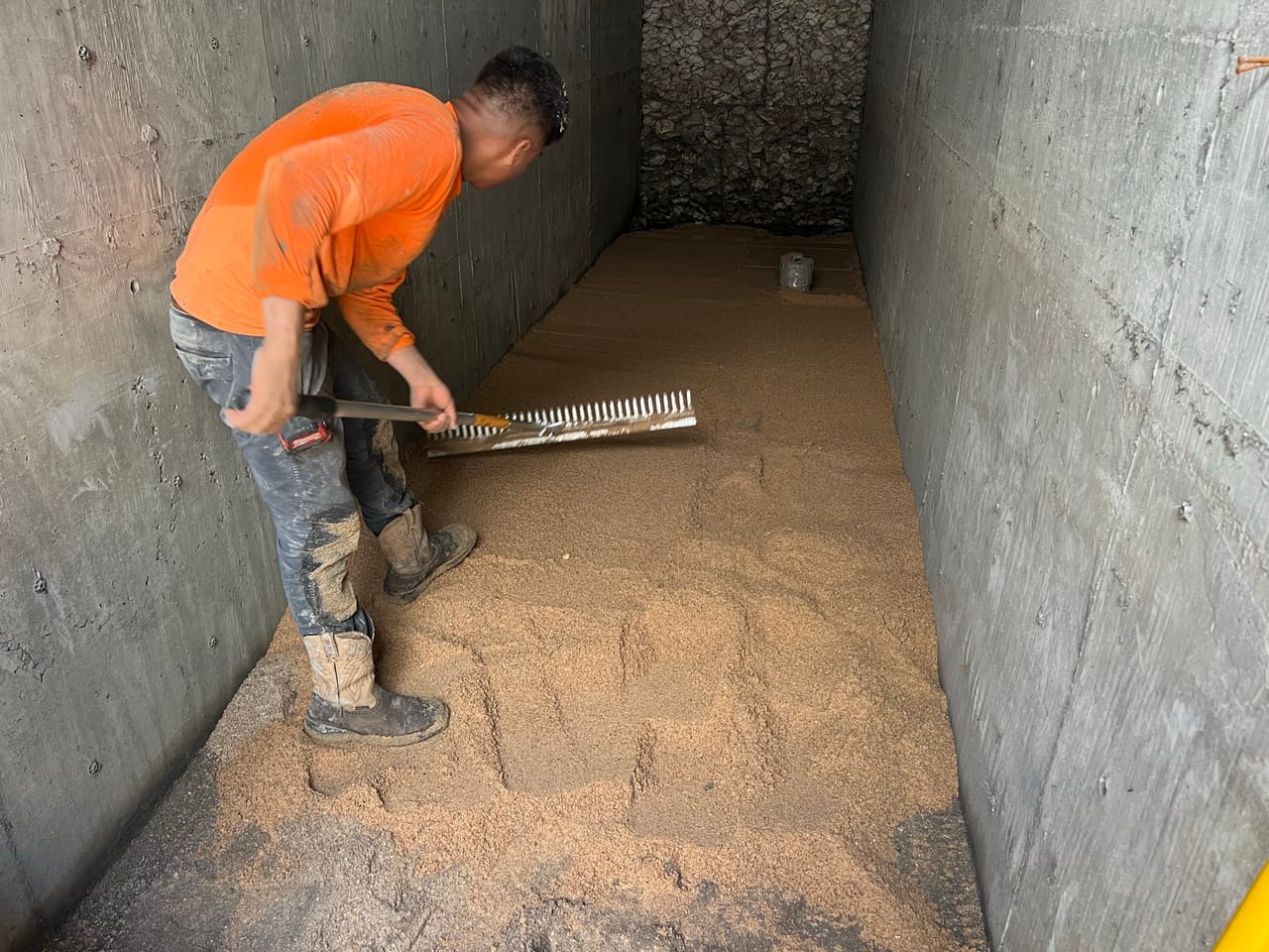 Worker raking sand media level inside a concrete stormwater vault in Kyle, TX